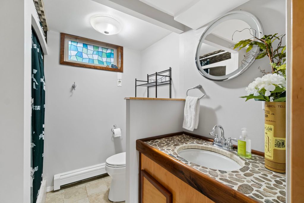 A bathroom with a concrete sink and tile counter top, toilet centered in the background.